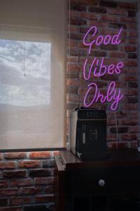 a neon sign that says good vibes only on a brick wall at Allure 23 in Gevgelija
