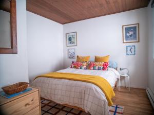Un dormitorio con una cama con una manta amarilla. en Chalet “Lendemain de ville” avec accès au lac, en Saint Adolphe D'Howard