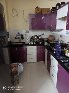 a kitchen with purple cabinets and a counter top at Adinath Residency in Jaipur