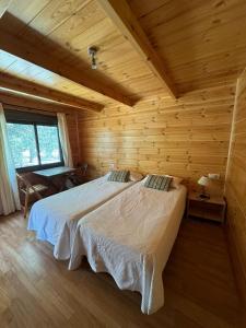 a bedroom with two beds in a log cabin at Hostal de Montaña Pous de la neu in Alfara de Carles