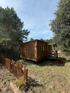 a wooden cabin in a field next to a fence at Hostal de Montaña Pous de la neu in Alfara de Carles