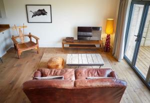 a living room with a leather couch and a chair at PigLets in Castle Acre