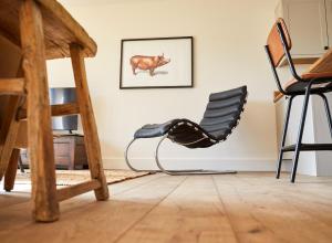 a chair in a room with a picture of a cow on the wall at PigLets in Castle Acre