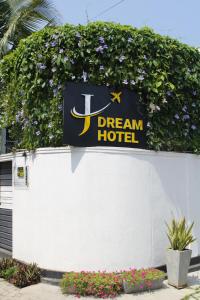 a dream hotel sign on a white wall with flowers at Airport J Dream Resort in Dewamottawa