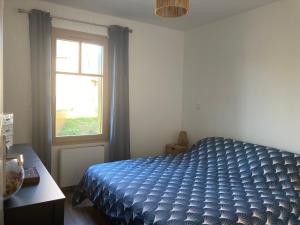 a bedroom with a blue bed and a window at Gîtes des Guettes in Saint-Suliac