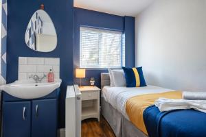 Dormitorio azul con cama y lavamanos en New - Stylish 4 bedroom House, Business & Leisure. Discount on long stays. By Jesswood Properties., en Southend-on-Sea