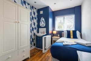 Dormitorio azul con cama y lavamanos en New - Stylish 4 bedroom House, Business & Leisure. Discount on long stays. By Jesswood Properties., en Southend-on-Sea