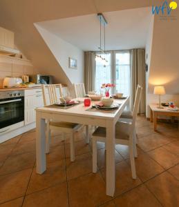 eine Küche mit einem weißen Tisch mit Stühlen und einem Esszimmer in der Unterkunft Villa Vogelsang Ferienwohnung 12 in Binz