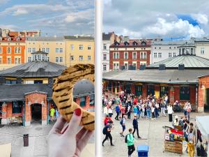 a person holding a donut in front of a crowd of people at GREEN APARTMENTS #Nowy Square, Kazimierz district in Krakow