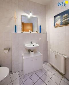 ein weißes Badezimmer mit einem Waschbecken und einem Spiegel in der Unterkunft Villa Vogelsang Ferienwohnung 12 in Binz