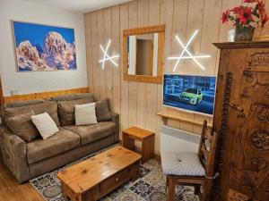 a living room with a couch and a flat screen tv at Appartement rénové près des pistes avec terrasse, ski, parking et cuisine équipée - FR-1-514-48 in Courchevel