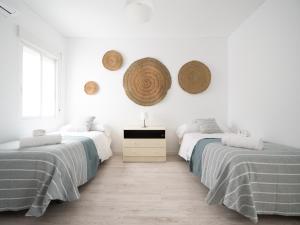 two beds in a white room with hats on the wall at Luxury Home Mezquita in Córdoba