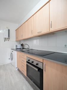 a kitchen with wooden cabinets and a sink and a dishwasher at Luxury Home Mezquita in Córdoba