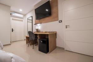 a bedroom with a desk and a tv on the wall at Hotel Bel Posto by Tandem in Realicó