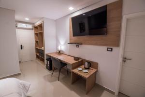 1 dormitorio con escritorio y TV en la pared en Hotel Bel Posto by Tandem en Realicó
