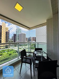 a balcony with a glass table and chairs and a view at Apartamento ao lado do Salvador Shopping 3 in Salvador