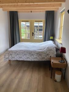 a bedroom with a large bed and two windows at Logeren bij De Soerensesteeg in Uddel