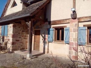 une maison avec des fenêtres à volets bleus et une porte dans l'établissement Maison du Bûcheron, à Beaulieu-sur-Dordogne