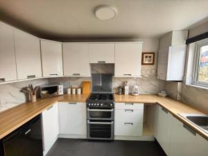 uma cozinha com armários brancos e um forno com placa de fogão em Haydon Hill House em Buckinghamshire