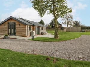 a log cabin with a tree and a gravel driveway at Medlands in Newent