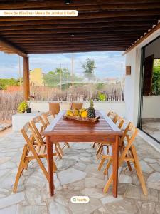 una mesa de madera con un bol de fruta en el patio en Casinha da Vila Taíba com piscina, en Taíba