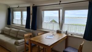 a living room with a table and a couch and two windows at Haus Westend in Baltrum