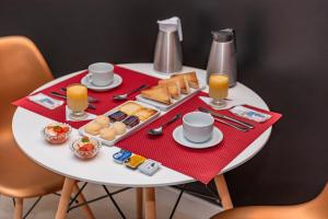 Assahi Motel (Adult Only) في فورتاليزا: طاولة بيضاء عليها طعام افطار ومشروبات