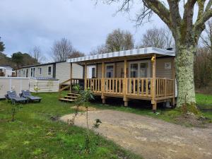 a mobile home with a deck and a tree at Vacances en Mobil home à Piriac sur mer in Piriac-sur-Mer