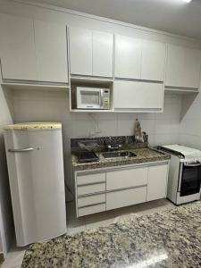 a kitchen with white cabinets and a sink and a microwave at Apto Apólo - 3 dorm Wifi in São Carlos