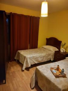 a bedroom with two beds and a table with a tray of fruit at Hostería Río Negro in Bárcena de Cicero