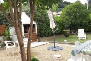 einen Hinterhof mit einem Sonnenschirm, einem Grill und einem Tisch in der Unterkunft Un logement dans pavillon Pèzenas in Pézenas