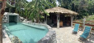 a swimming pool with two chairs and a hut at Mabrika Resort Dominica in Guillet