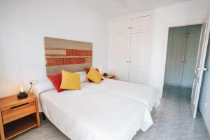 Un dormitorio con una cama blanca con almohadas amarillas y rojas en Villa Julia, ¡Beach, pool, sun and rest!, en Málaga 19 fotos más