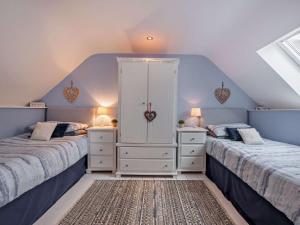 a bedroom with two beds and a white cabinet at 2 Bed in Neyland 43430 in Llanstadwell