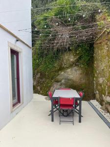 uma mesa com uma cadeira vermelha ao lado de uma parede em Bloom Cottage I - Sintra montain em Sintra