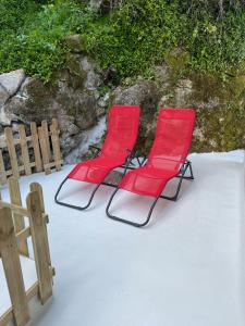 dwa czerwone krzesła siedzące na śniegu obok płotu w obiekcie Bloom Cottage I - Sintra montain w mieście Sintra