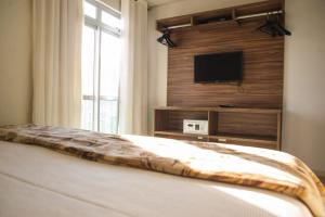 a bedroom with a bed with a television on a wall at Manhattan Apart Hotel in Caratinga