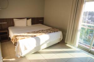 a bed in a room with a large window at Manhattan Apart Hotel in Caratinga