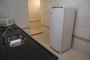 a kitchen with a sink and a refrigerator at Manhattan Apart Hotel in Caratinga