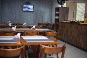 a dining room with tables and chairs and a counter at Manhattan Apart Hotel in Caratinga