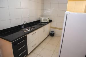 a small kitchen with a sink and a refrigerator at Manhattan Apart Hotel in Caratinga