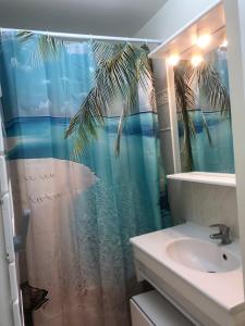 La salle de bains est pourvue d'un rideau de douche avec un palmier. dans l'établissement Jeux olympiques 2024, à Montigny-le-Bretonneux