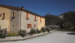 a stone building with orange shuttered windows and plants at Tenuta Le Garzaie - Villa Furlo in Fermignano