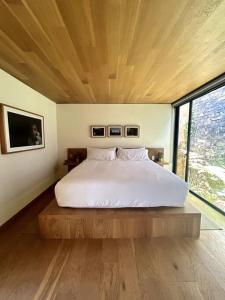 ein großes Bett in einem Zimmer mit einem großen Fenster in der Unterkunft Cabaña Roble Boutique en Avándaro, Valle de Bravo in Valle de Bravo