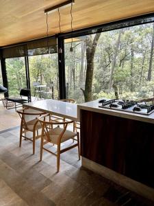 a kitchen with a stove and a table with chairs at Cabaña Roble Boutique en Avándaro, Valle de Bravo in Valle de Bravo