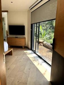 a living room with a television and a large window at Cabaña Roble Boutique en Avándaro, Valle de Bravo in Valle de Bravo
