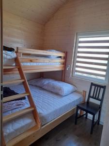 a bedroom with two bunk beds and a chair at Malwa Domki Letniskowe in Rusinowo