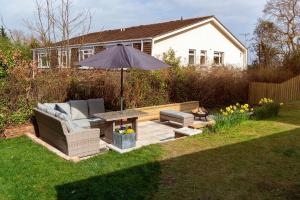 a patio with an umbrella and a couch and a table at Heathgate House Apartment in Budleigh Salterton