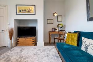 a living room with a blue couch and a television at Heathgate House Apartment in Budleigh Salterton