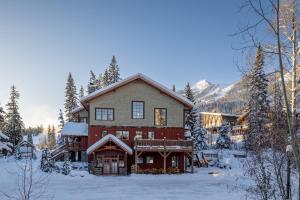 ein großes rotes Haus mit Schnee auf dem Boden in der Unterkunft Copper Horse Lodge in Golden